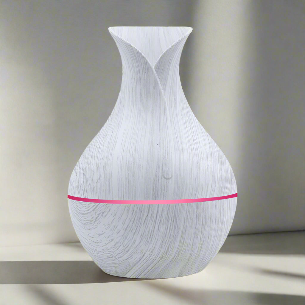 An image of a household humidifier designed to resemble a vase with wood grain finish, featuring a pink band around the middle.